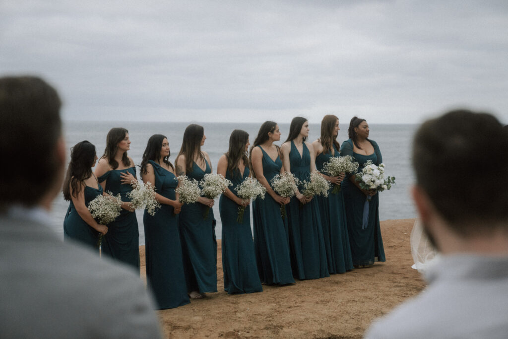 bridesmaids standing beside bride at oceanside wedding