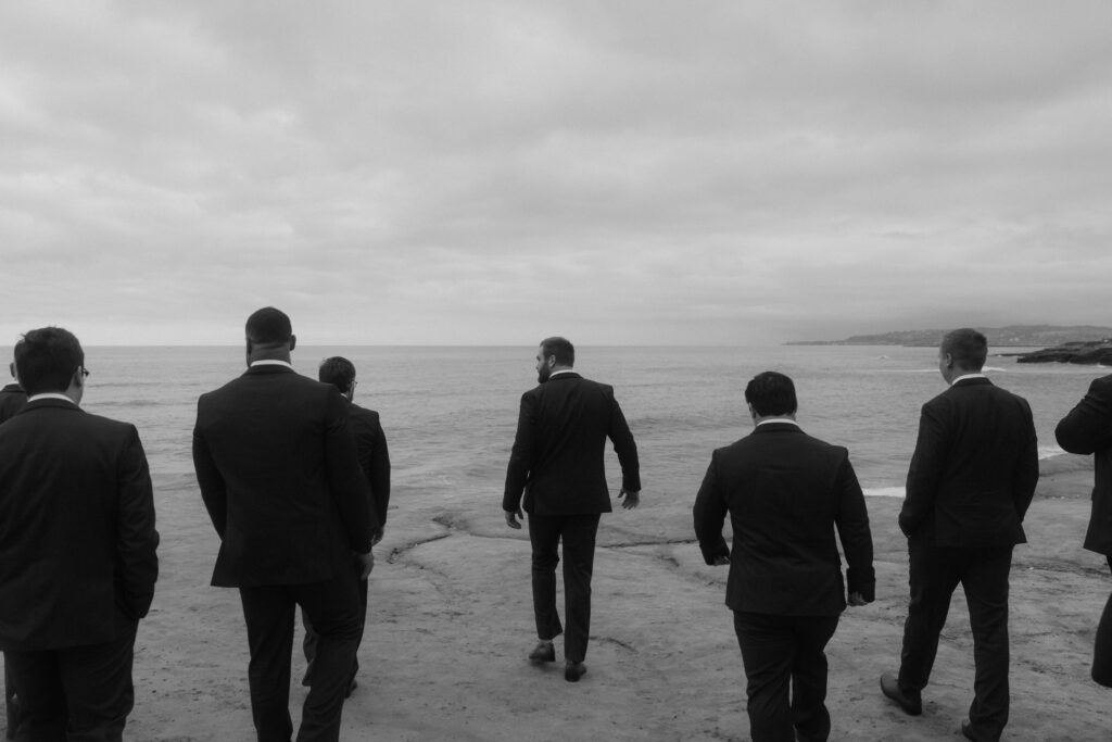 groom and groomsmen walking away from camera along cliffside in san diego