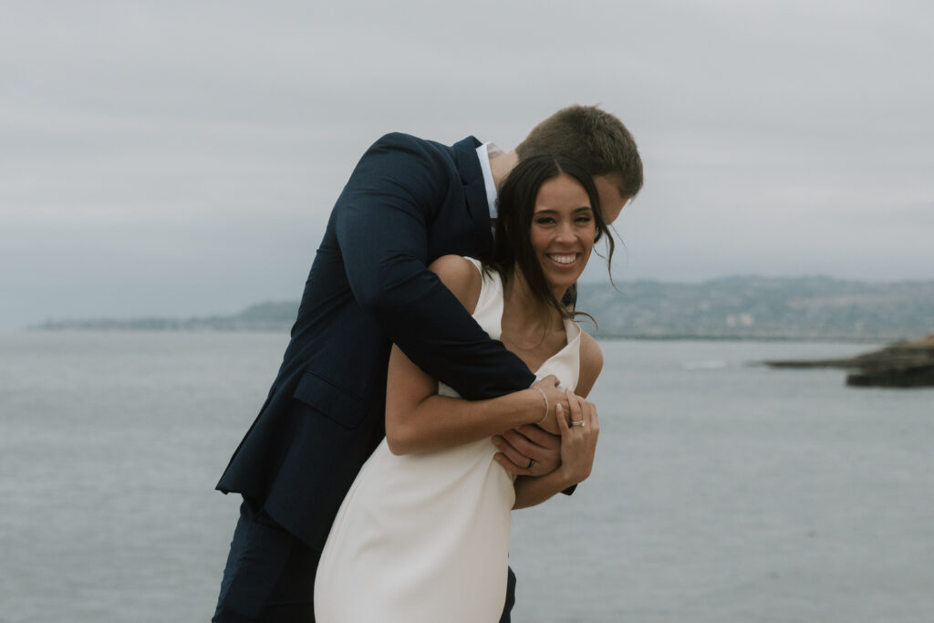 groom hugging bride from behind while she laughs
