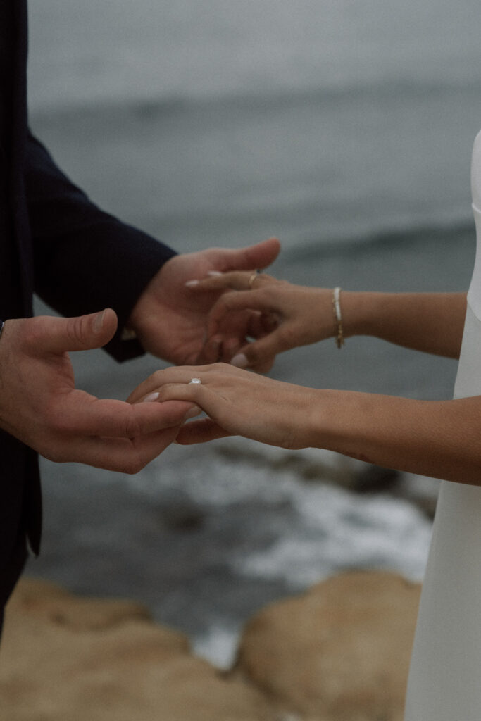 bride and groom holding hands with ocean in the background