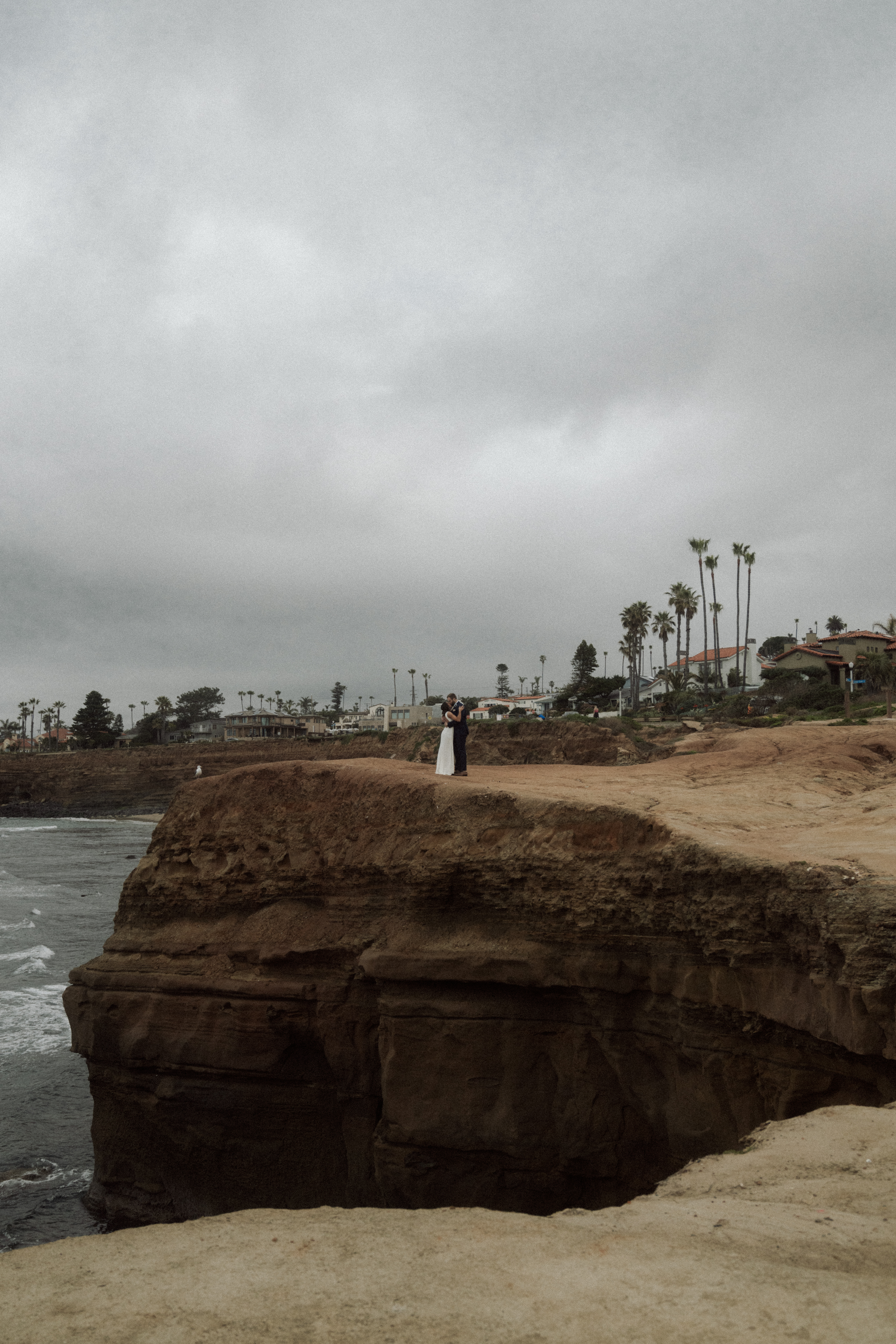bride and groom standing on edge of cliff in san diego