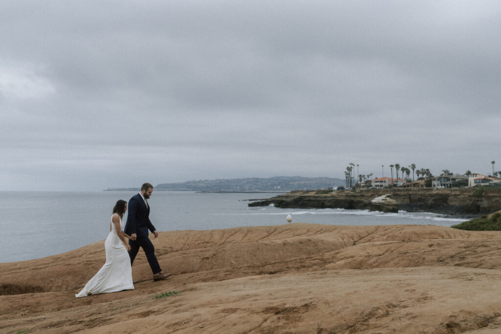 bride and groom walking along sunset cliffs at sunrise