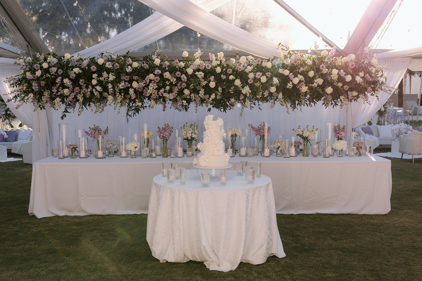 Luxury Alys Beach wedding reception under a clear tent with hanging purple florals and candlelit tables in Central Park.