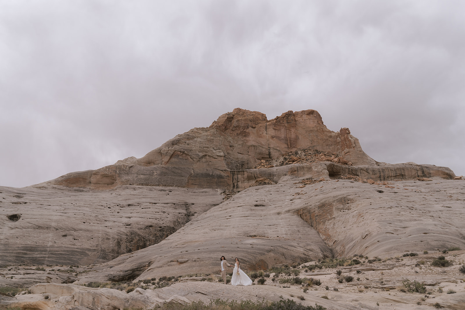 Couple walking hand-in-hand through desert canyon with smooth sculptural rock formations