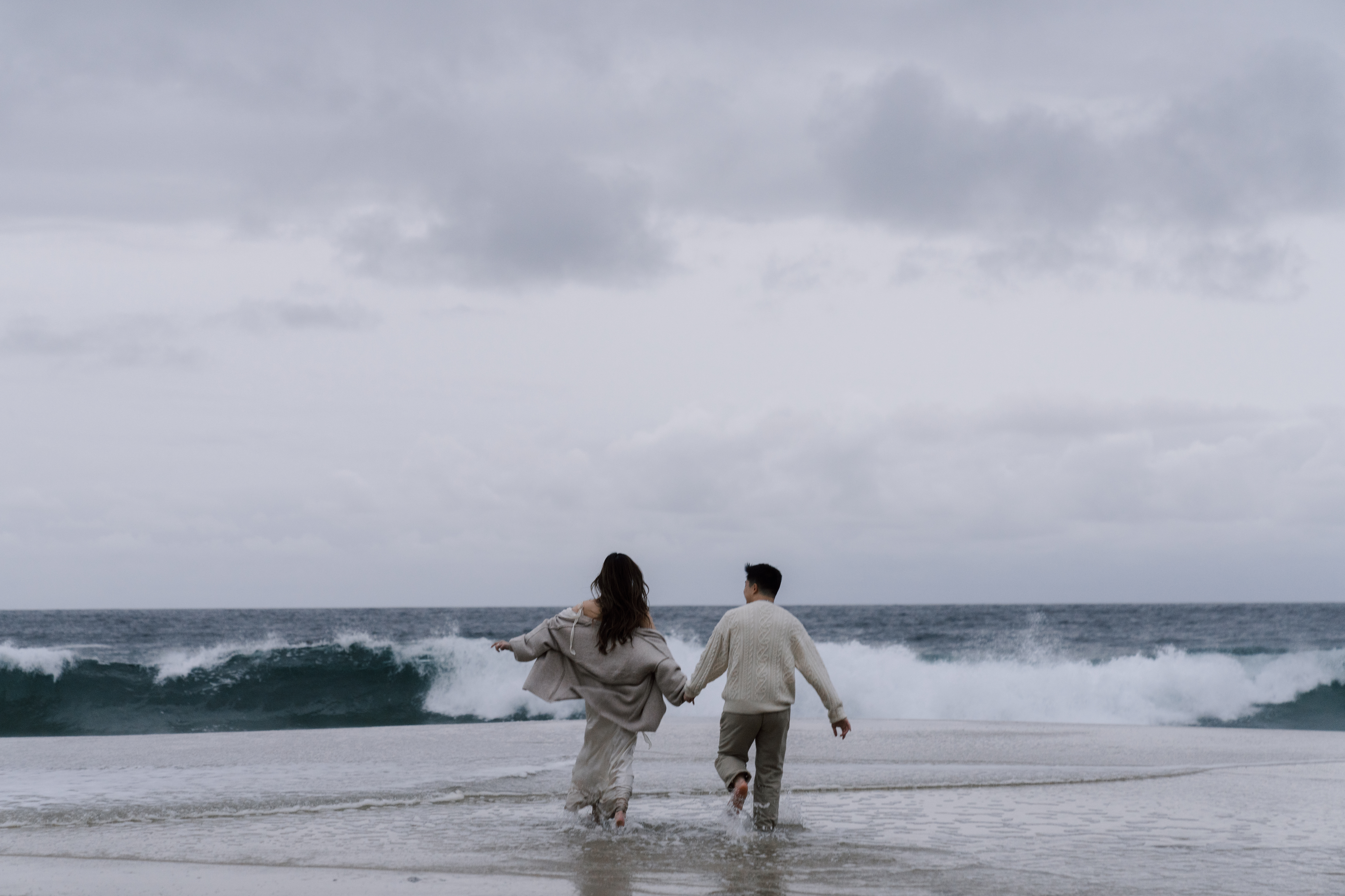 Couple running on California coast while holding hands