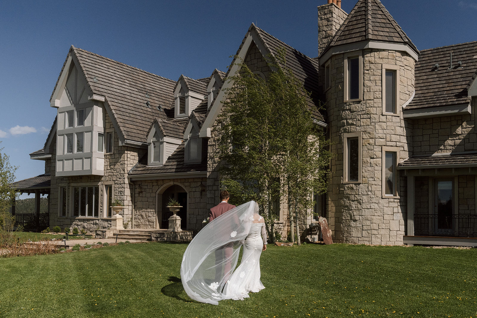 Bride and groom walking in front of Greystone Castle Boulder