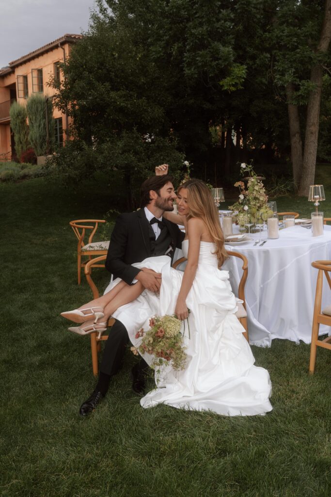 Bride and groom seated at an elegantly styled reception table with soft florals, taper candles, and views of the Italian countryside at their villa wedding