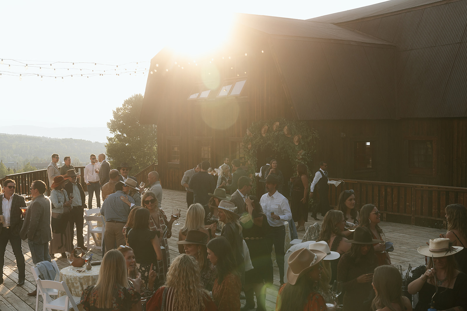 Guests in Western attire enjoying the sunset cocktail hour on the barn’s deck at Gorrono Ranch.