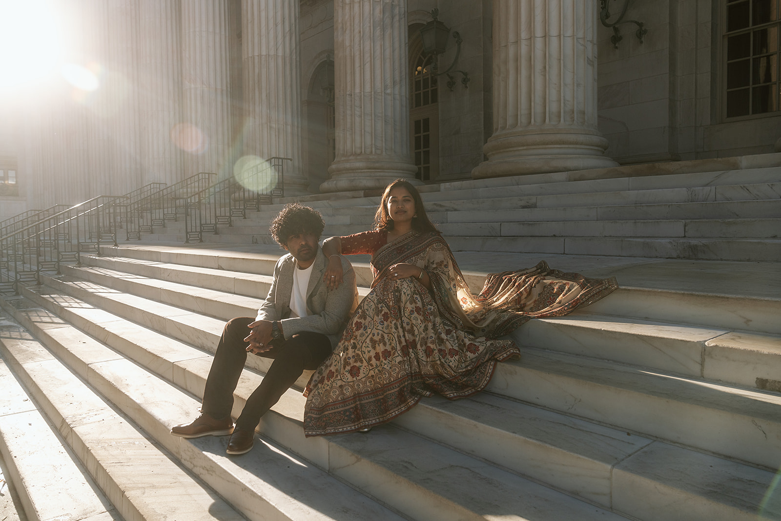 Couple sitting outside the Byron White Courthouse in downtown Denver during golden hour, framed by tall white columns and soft evening light.